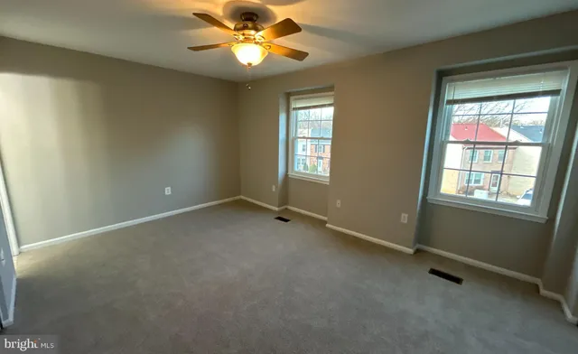 an empty room with windows and fan