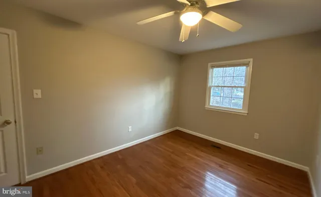 an empty room with a window and a chandelier fan