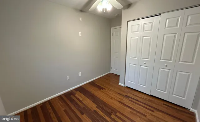 an empty room with a chandelier fan and windows