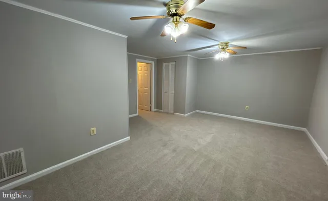 an empty room with a chandelier fan and windows