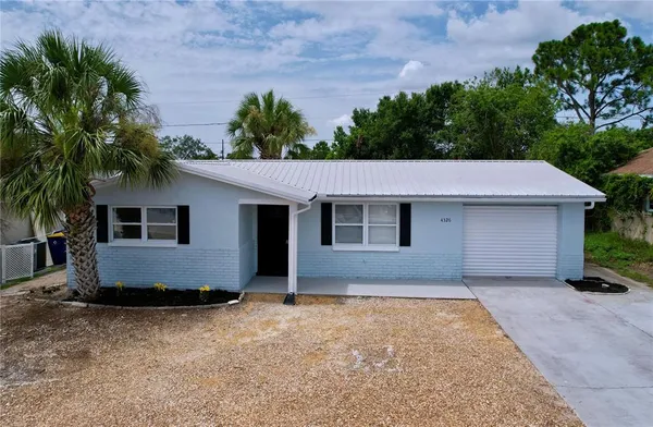 a view of house with yard and trees in the background