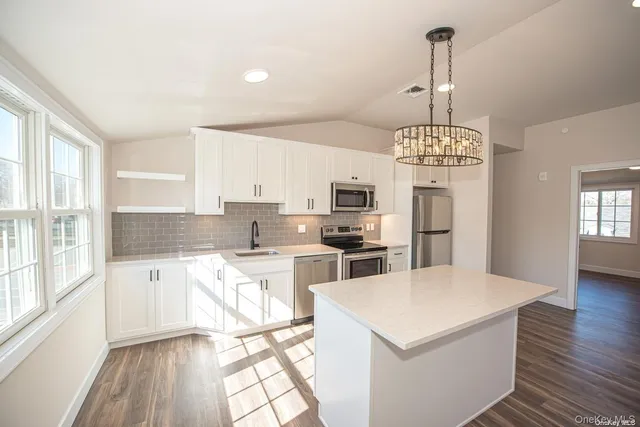 a kitchen with stainless steel appliances a stove a refrigerator sink and white cabinets