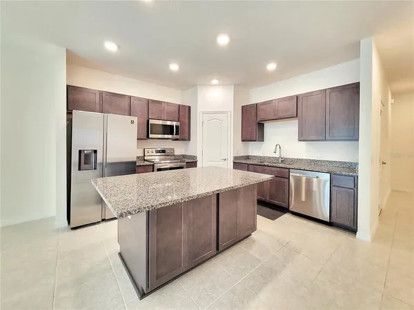 a kitchen with stainless steel appliances granite countertop a stove top oven a sink and a refrigerator