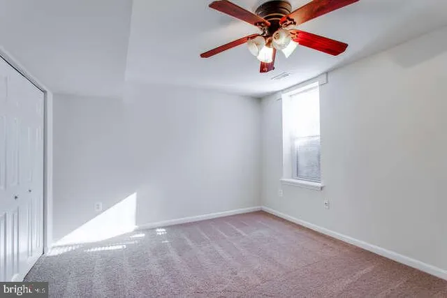an empty room with ceiling fan and window