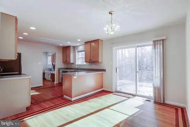 a kitchen with stainless steel appliances granite countertop a refrigerator a sink dishwasher a stove and white cabinets with wooden floor