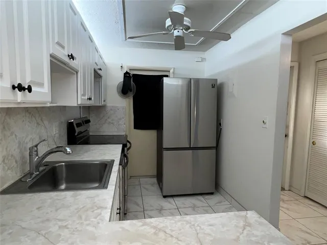 a kitchen with stainless steel appliances granite countertop a refrigerator a sink a stove a microwave oven with white cabinets