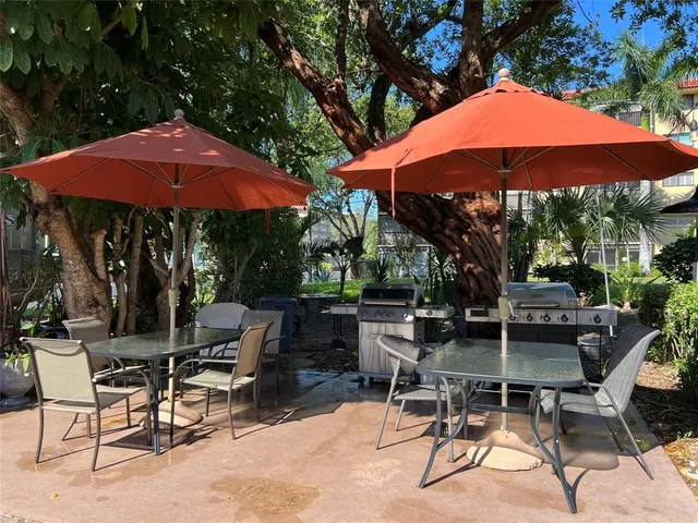 a view of patio with chairs and table under an umbrella