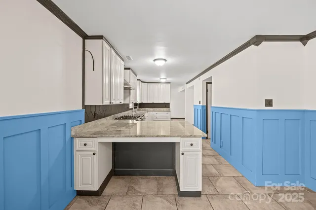 a kitchen with granite countertop a sink and white cabinets