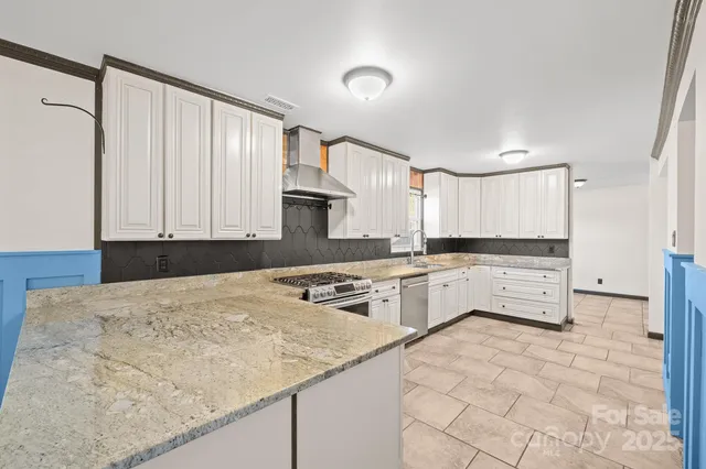 a kitchen with granite countertop white cabinets and stainless steel appliances