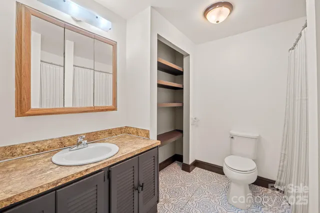a view of an empty room with wooden floor and a ceiling fan