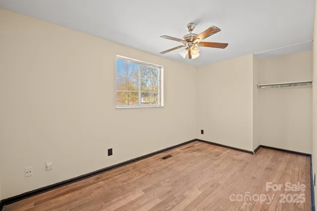 an empty room with window and ceiling fan