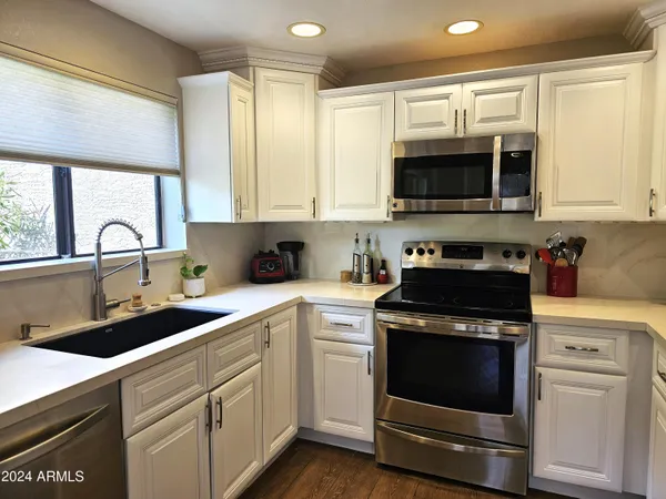 a kitchen with cabinets stainless steel appliances a sink and a window