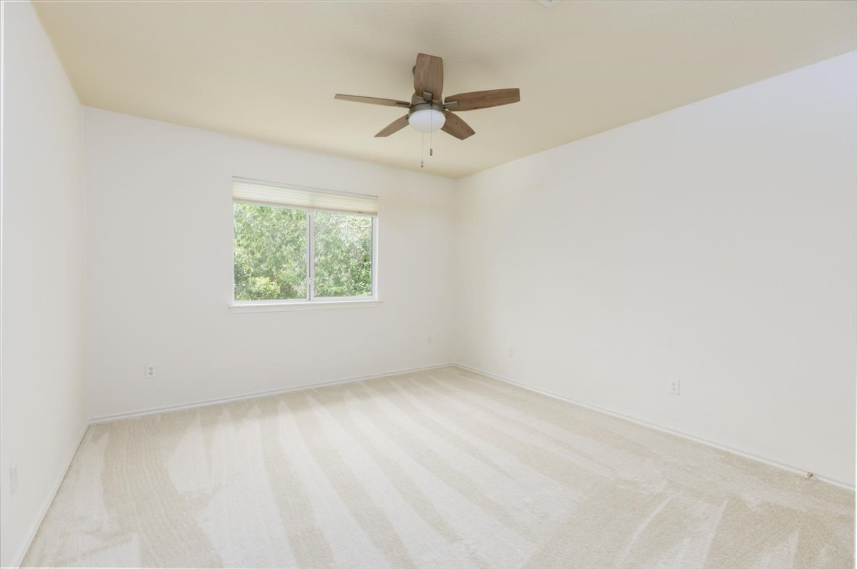 7136 Ridge Oak Road Austin, TX 78749 - Photo 17 of 28 A well-lit bedroom features plush carpeting and a tranquil window view of surrounding trees.