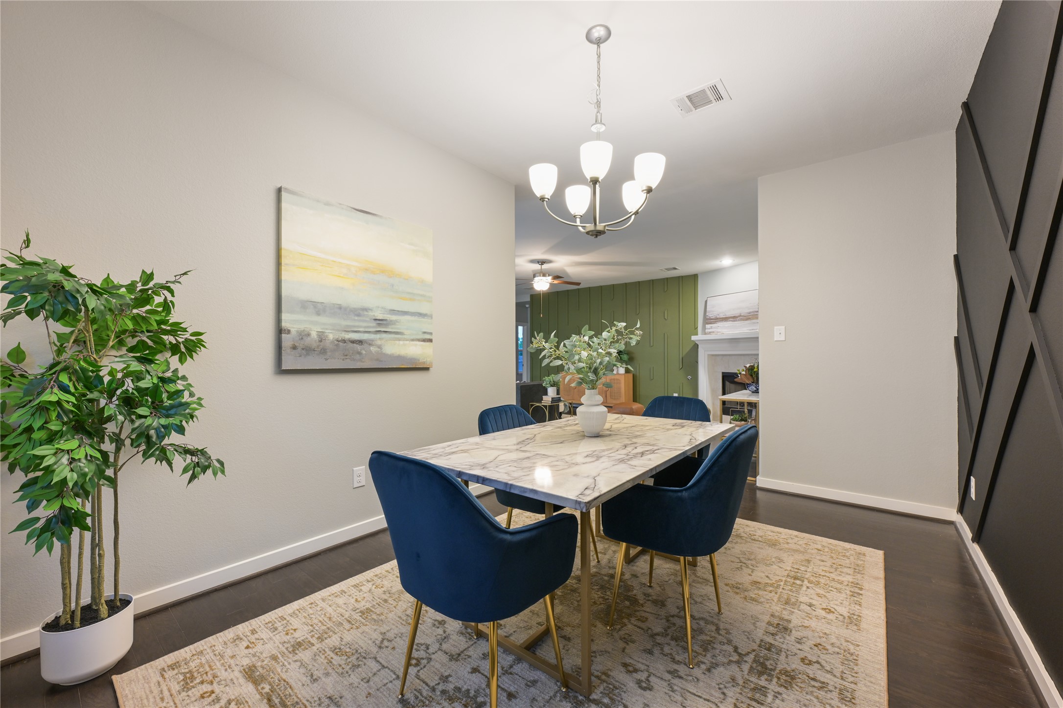 188 Nautical Loop Kyle, TX 78640 - Photo 12 of 38 Hardwood floors and a sophisticated chandelier define this elegant dining space, seamlessly connecting to a living area with a fireplace.