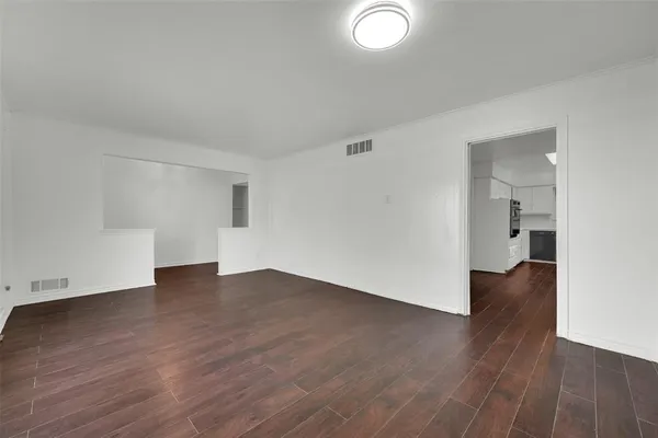 an empty room with wooden floor & windows