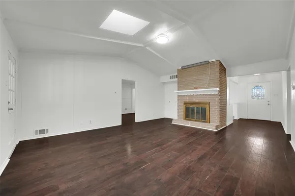 an empty room with wooden floor and fireplace