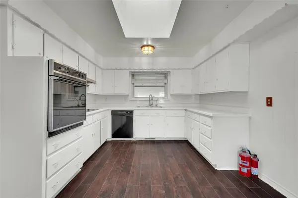 a kitchen with granite countertop a stove top oven a sink dishwasher and white cabinets with wooden floor