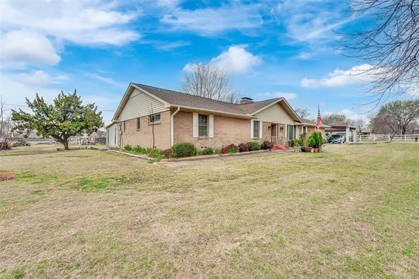 a front view of house with yard and trees in the background