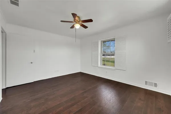 a view of empty room with wooden floor and fan