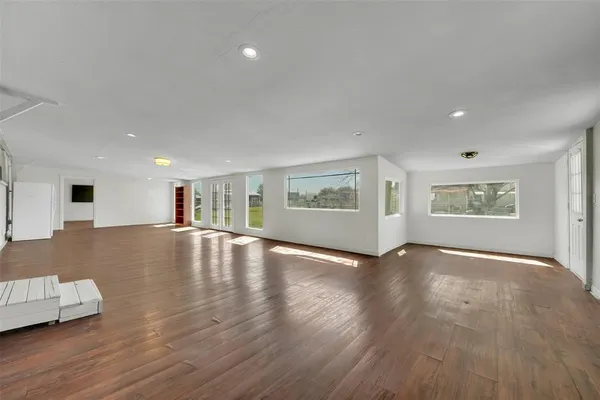 a view of an empty room with window and wooden floor