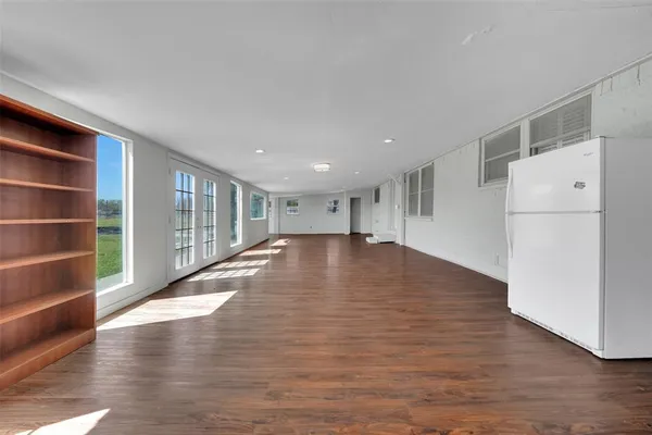 a view of empty room with wooden floor and electronic appliances
