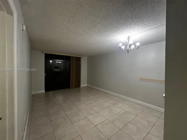an empty room with chandelier fan and wooden floor