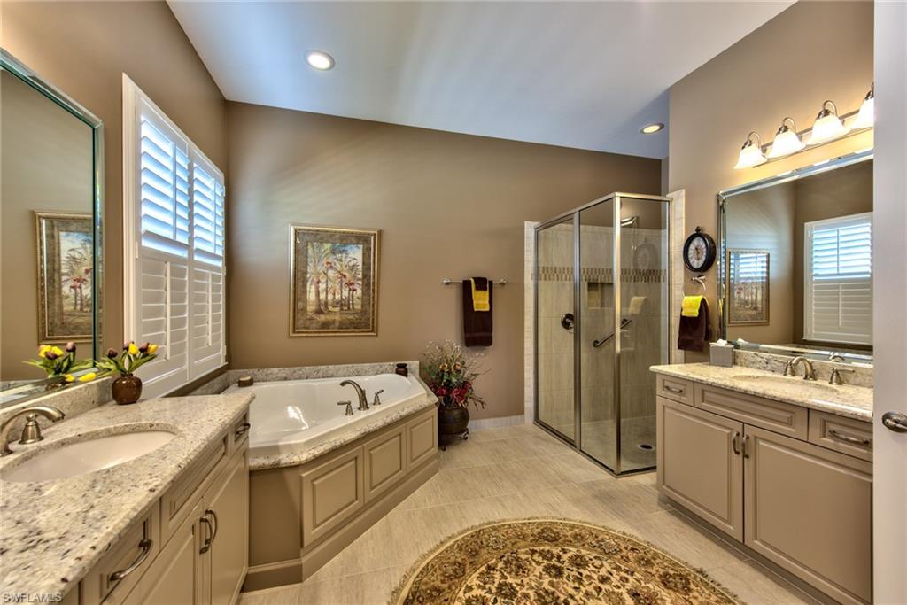 3424 Atlantic Circle Naples, FL 34119 - Photo 9 of 14 a large bathroom with a granite countertop tub sink and mirror