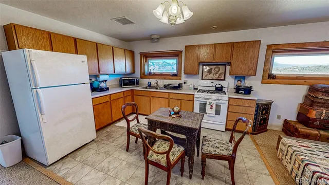 a kitchen with stainless steel appliances granite countertop a refrigerator a sink dishwasher a stove and a dining table with wooden cabinet