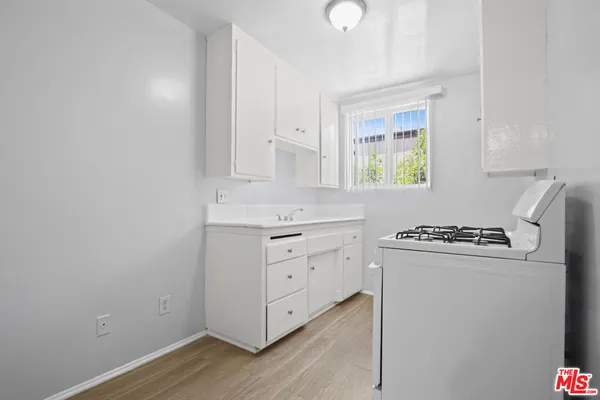 a kitchen with white cabinets a sink appliances and a window