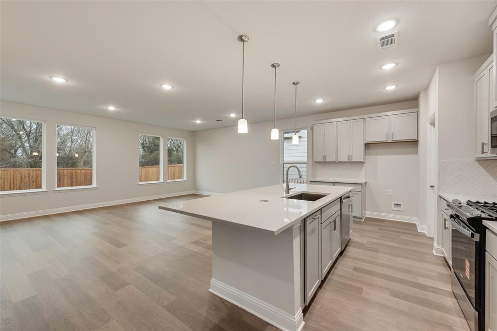 1013 Canoe Way Crowley, TX 76036 - Photo 4 of 26 a kitchen with a stove a sink a center island and wooden floor