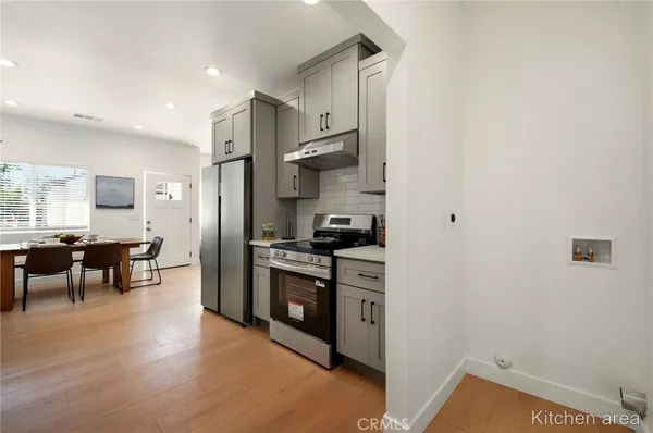 a kitchen with stainless steel appliances granite countertop a stove refrigerator and a refrigerator with wooden floor