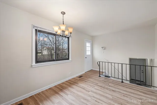 a view of a bedroom with wooden floor windows and a chandelier