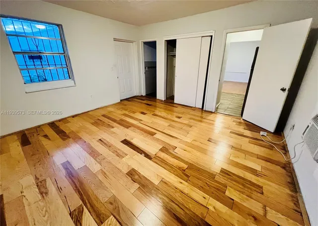 a bedroom with a bed and hardwood floor