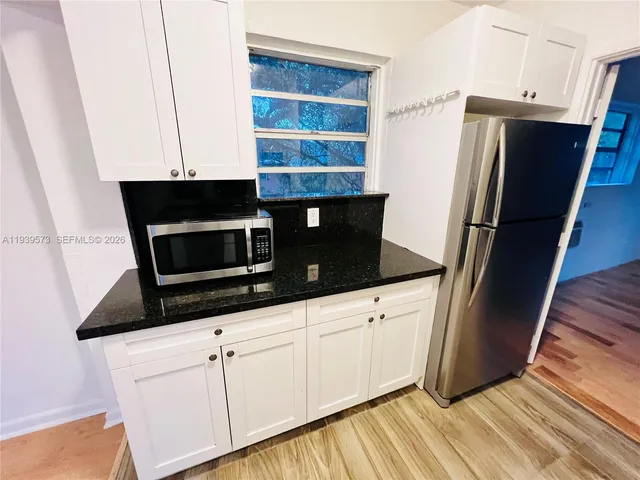 a kitchen with granite countertop a refrigerator and a sink
