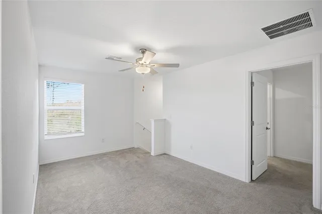an empty room with windows and fan