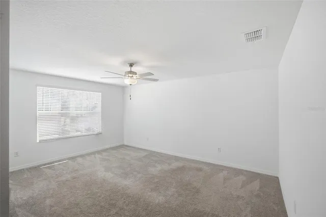 an empty room with windows and fan