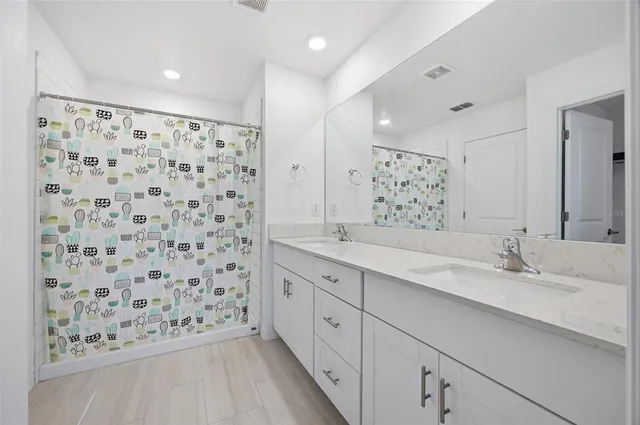 a bathroom with a double vanity sink mirror and shower