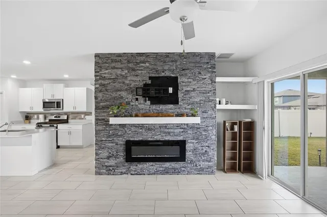 a living room with stainless steel appliances furniture a fireplace and a counter top