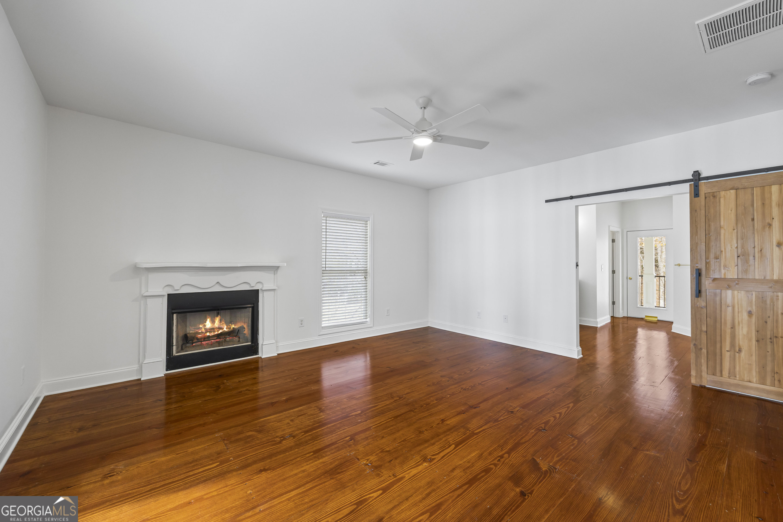 1270 Swords Road Greensboro, GA 30642 - Photo 27 of 41 an empty room with wooden floor fireplace and windows