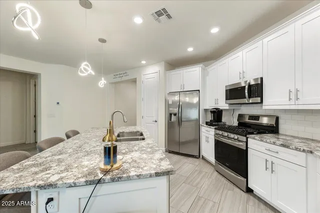 a kitchen with granite countertop a sink stainless steel appliances and white cabinets