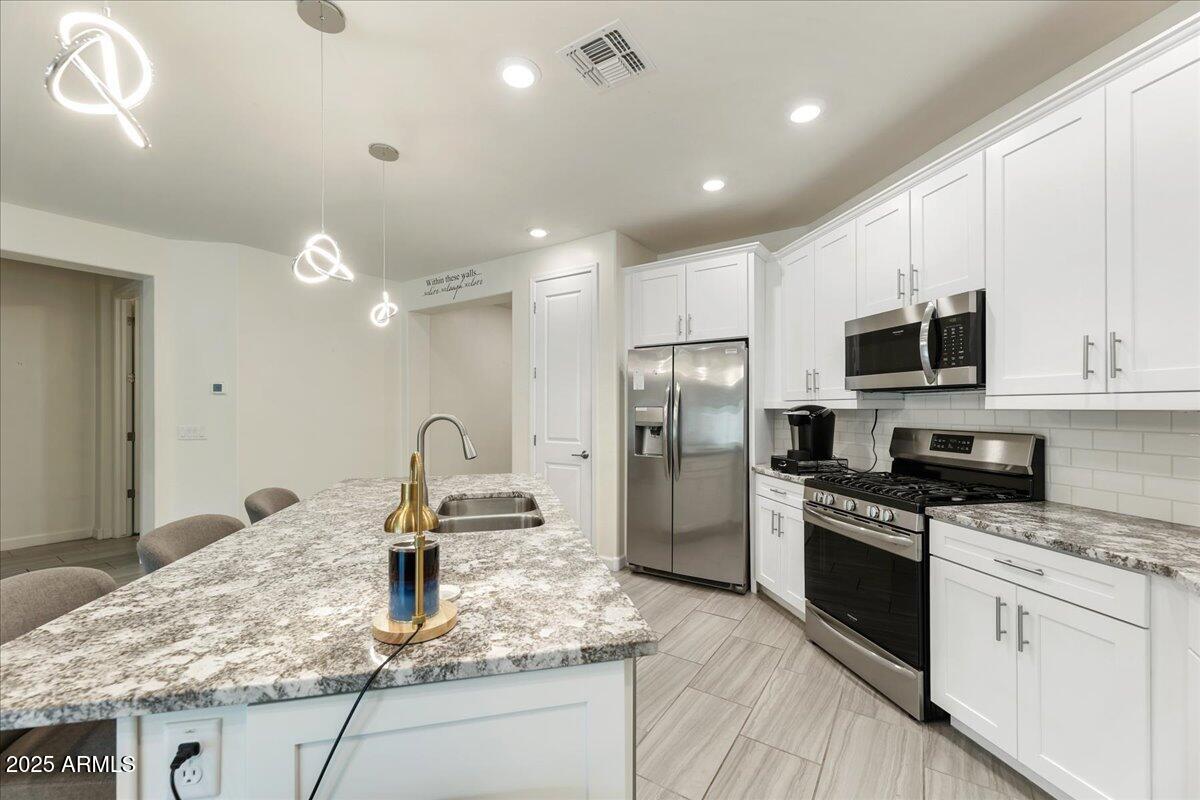 2745 West Pollack Street Phoenix, AZ 85041 - Photo 5 of 20 a kitchen with granite countertop a sink stainless steel appliances and white cabinets