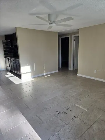 a view of a refrigerator in kitchen and an empty room with wooden floor