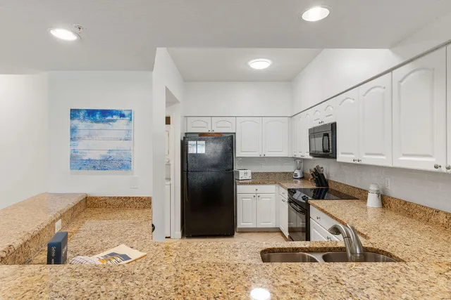 a kitchen with stainless steel appliances kitchen island granite countertop a refrigerator and a stove top oven