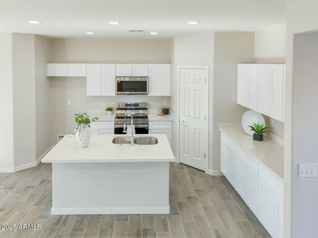 a large white kitchen with kitchen island white cabinets and refrigerator