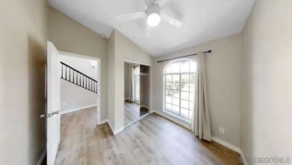a view of empty room with wooden floor and fan