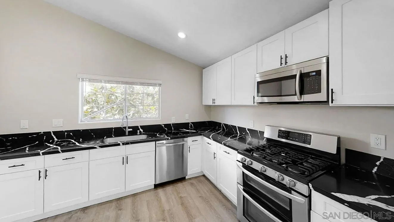 6497-99 Montezuma Road San Diego, CA 92115 - Photo 5 of 23 a kitchen with granite countertop white cabinets and black appliances