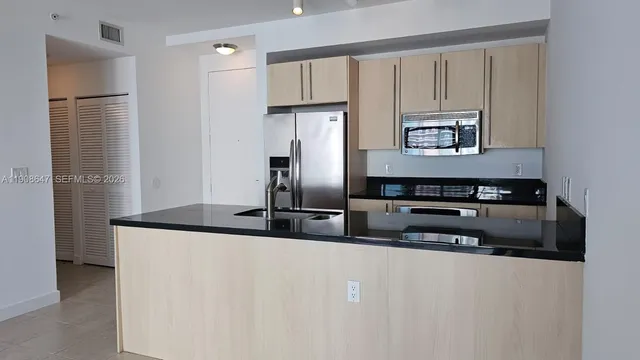 a kitchen with stainless steel appliances granite countertop a refrigerator a stove and a sink with wooden floor