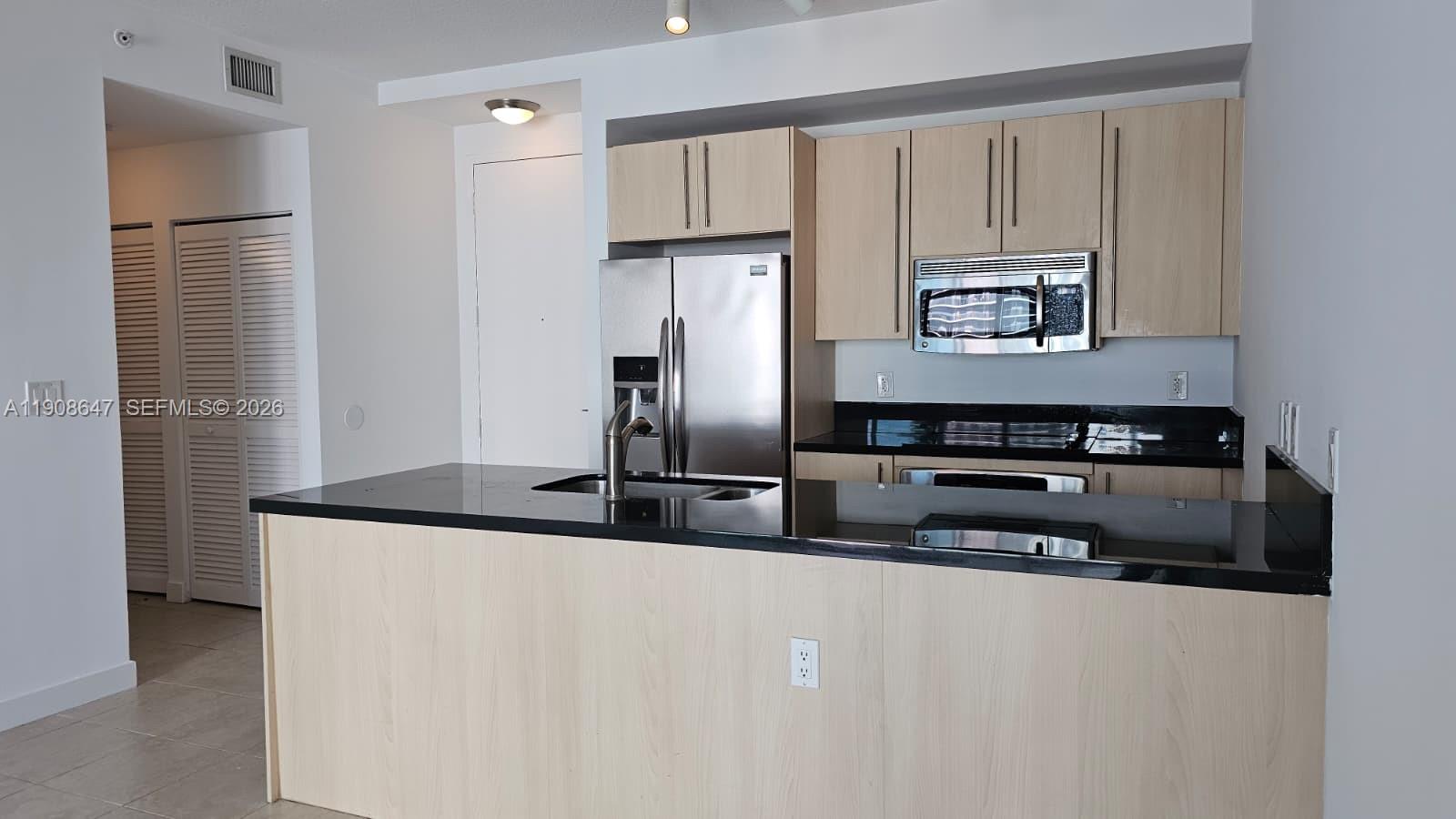 1111 Southwest 1st Avenue, Unit 2124N Miami, FL 33130 - Photo 1 of 34 a kitchen with stainless steel appliances granite countertop a refrigerator a stove and a sink with wooden floor