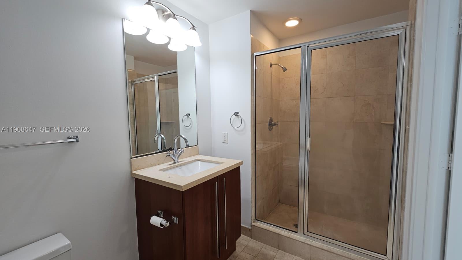 1111 Southwest 1st Avenue, Unit 2124N Miami, FL 33130 - Photo 13 of 34 a bathroom with a shower sink vanity and mirror
