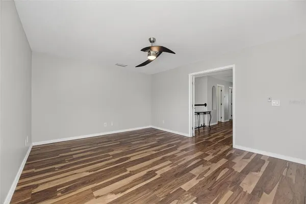 an empty room with a chandelier fan and windows